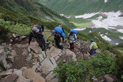 岩の多い道が続く登山道を登っている写真