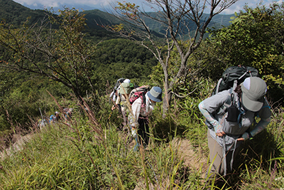 見晴らしの良くなってきた登山道を登っている写真