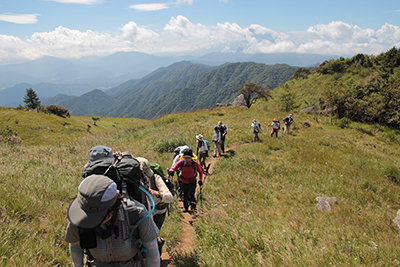 白谷丸と富士山を背に草原を登っている写真