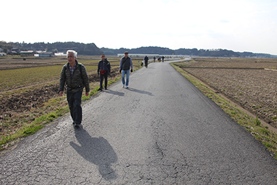 広い田畑の中の舗装道路を歩いている写真
