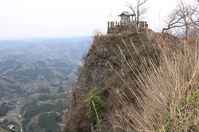 高度感抜群の山頂の祠の横に座っているＭ君の写真