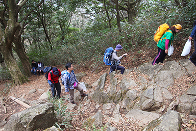 岩の多い登山道を登るメンバーの写真