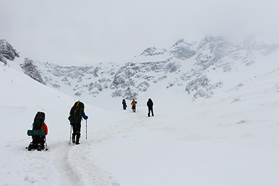 雪の降る中を涸沢ヒュッテ手前を登っている人たちの写真