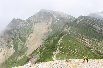 杓子岳を背に稜線を登っている写真