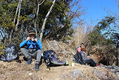 高根山の南側で風をよけて昼食中の写真