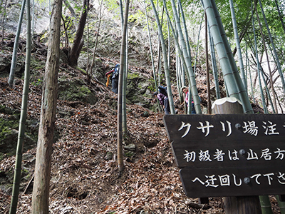 Iさんが撮影した迂回路を示す案内板と鎖場を登り始めたメンバーの写真