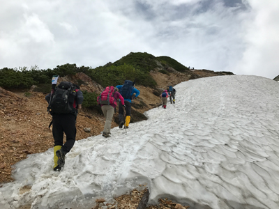 Kさんが撮影した山頂を目指して雪渓を上っている写真