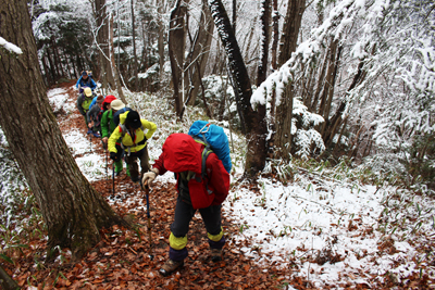 雪の増えてきた登山道を登っている写真