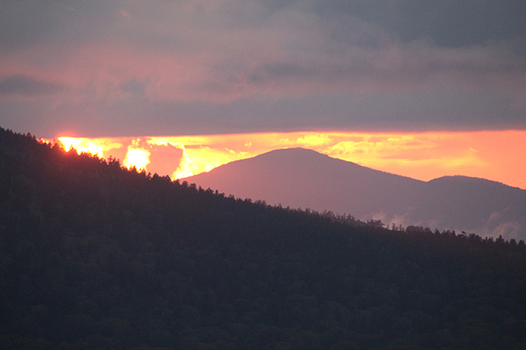 雲の切れ間から見えた森吉山と夕日の写真